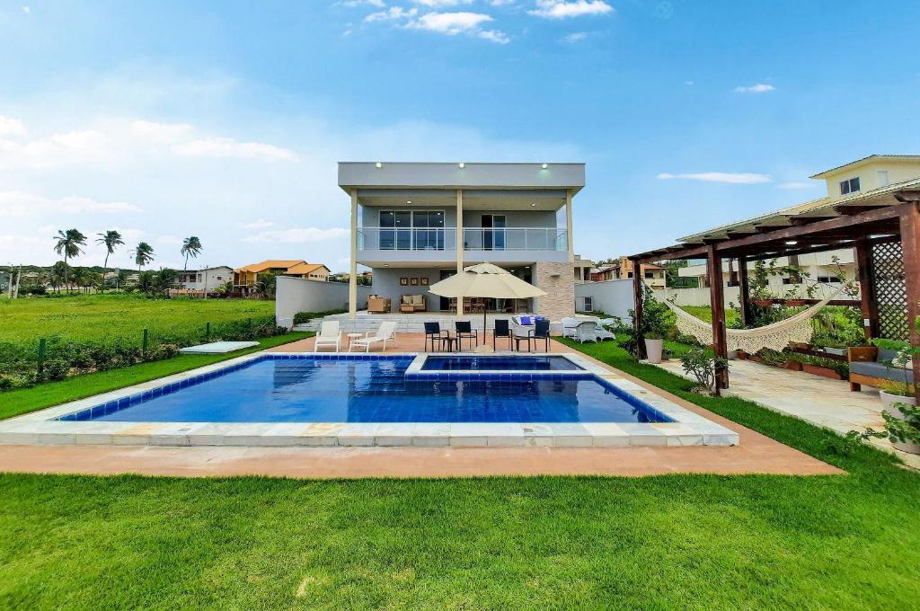 een huis met een zwembad in de tuin bij Summerville Mansão PéNaAreia Piscina BeachTennis in Cumbuco
