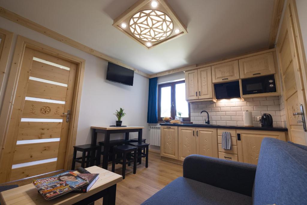 a kitchen with wooden cabinets and a table and chairs at Wierchowe Apartamenty in Leśnica