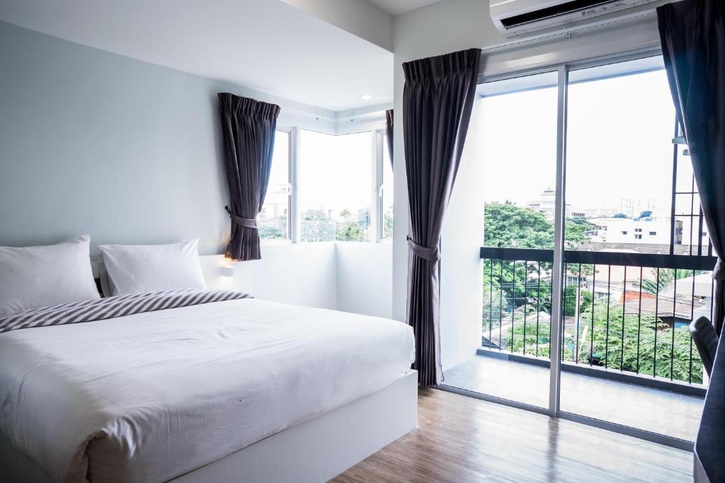 a bedroom with a white bed and a large window at Vanilla Residence Chiangmai in Chiang Mai