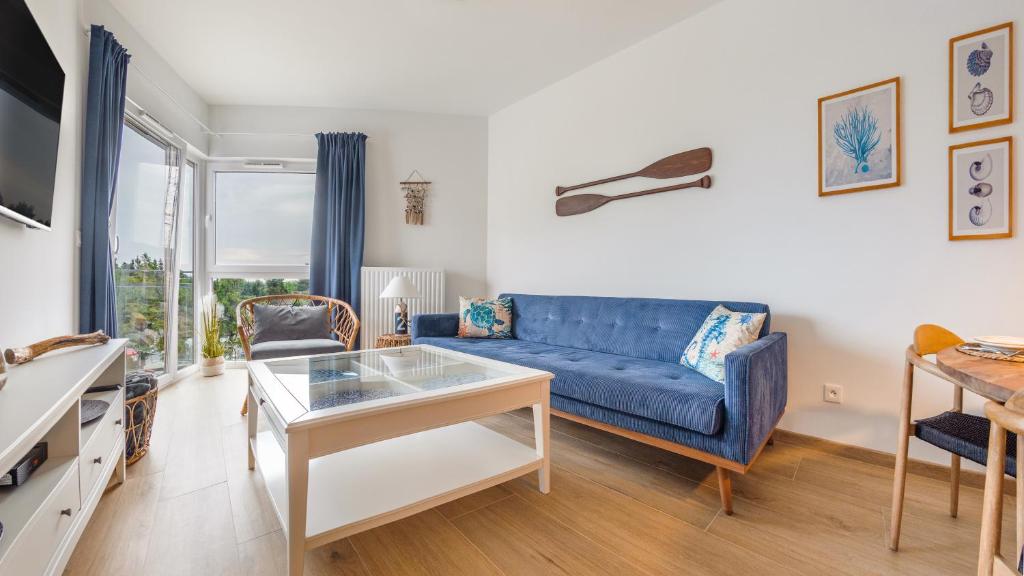 a living room with a blue couch and a table at Apartamenty Sun & Snow Let's Sea Baltic Park in Gąski