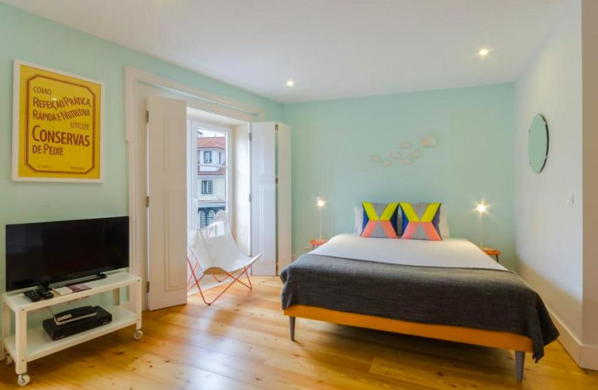 a bedroom with a bed and a flat screen tv at Light House Apartments - Casas da Baixa in Lisbon