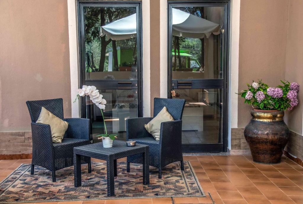 a porch with chairs and a table and a vase with flowers at Hotel L'Oleandro in Villasimius