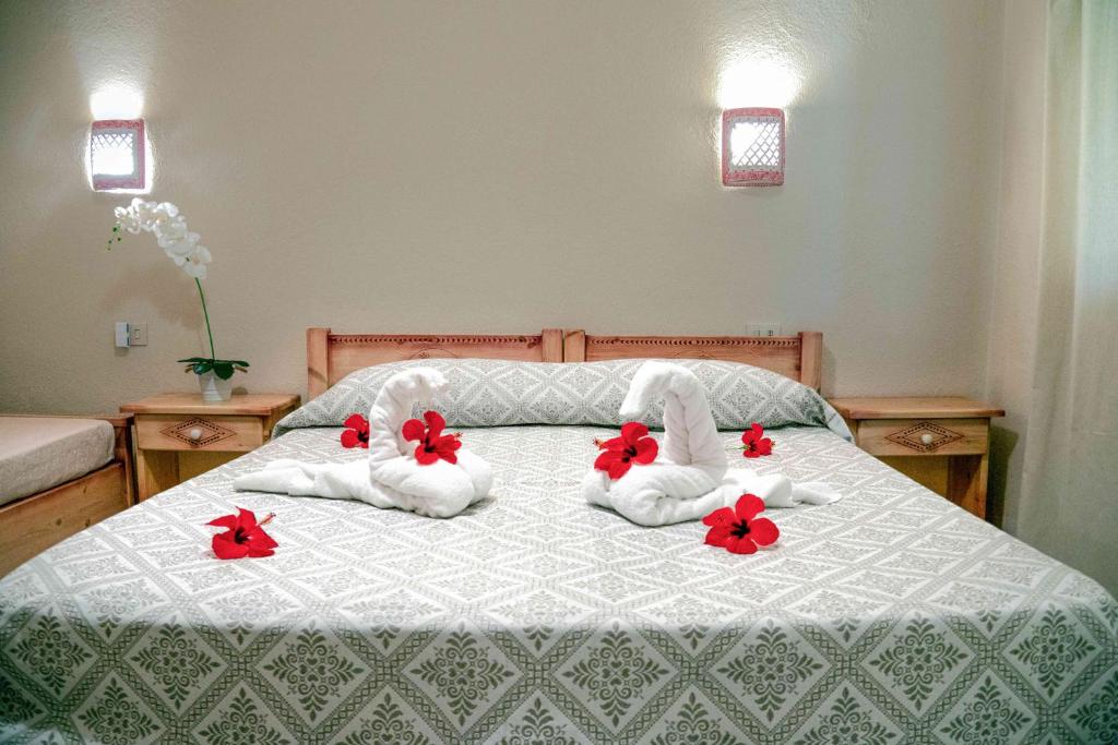 a bed with towels and red flowers on it at Hotel L'Oleandro in Villasimius