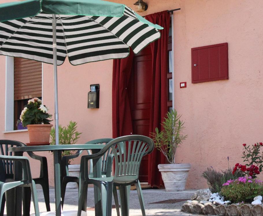 una mesa y sillas con una sombrilla en el patio en appartamento la Bastia fra il lago di Garda e Brescia città, en Nuvolento