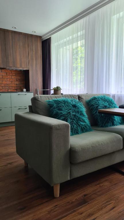 a couch with blue pillows in a living room at Mona Apartamentai in Telšiai