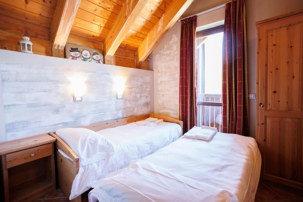 2 łóżka w małym pokoju z oknem w obiekcie Residence Stalle Lunghe w mieście Prato Nevoso