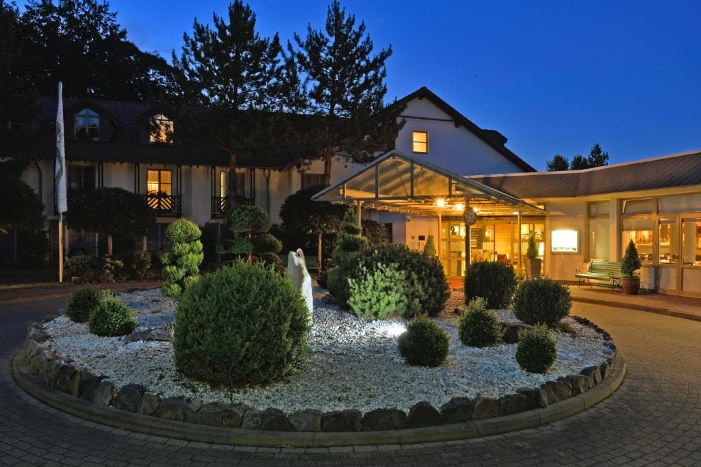 a house with a garden in front of a building at Landhotel Schnuck in Schneverdingen