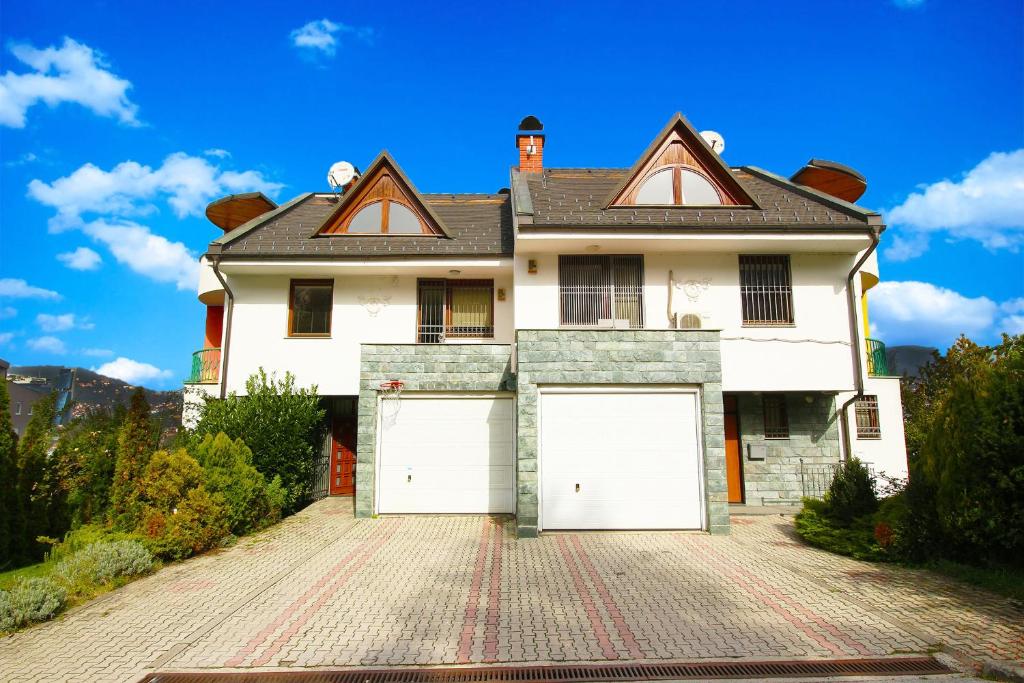 a large white house with two white garage doors at Villa Skenderija east by Poppy Sarajevo in Sarajevo