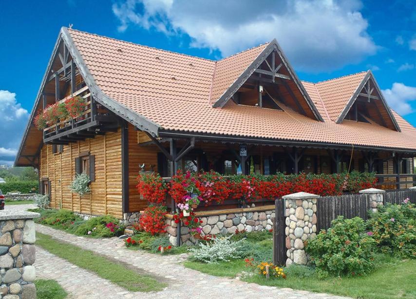 een houten huis met bloemen ervoor bij Marina Lester House in Rydzewo