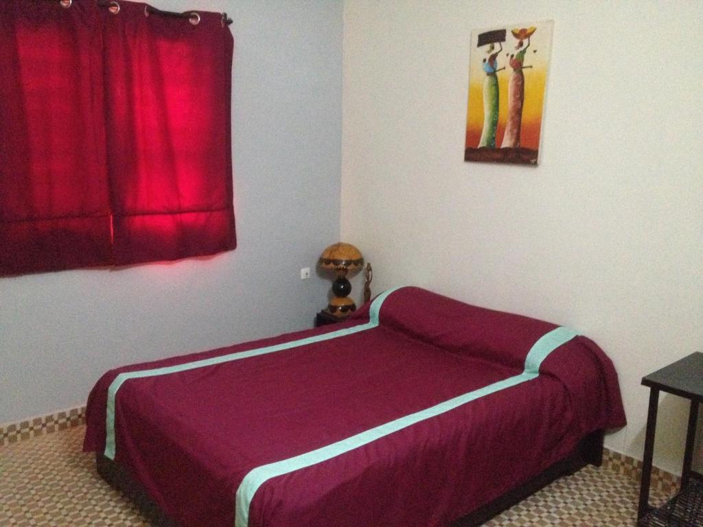1 dormitorio con cama morada y cortina roja en Hotel Kavana en Uagadugú