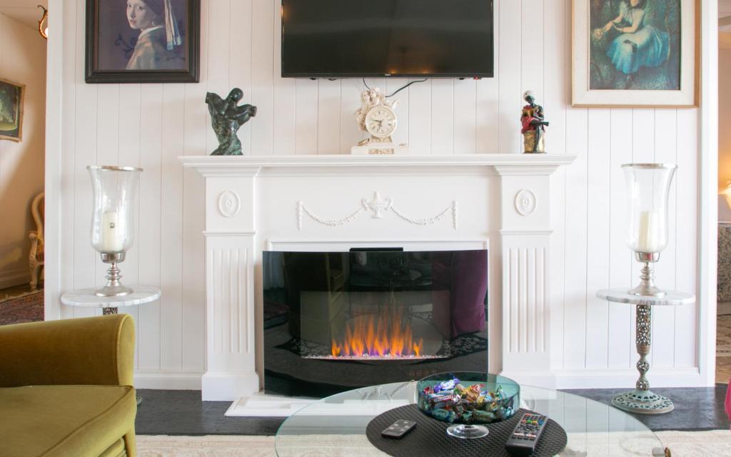 a living room with a fireplace with a tv above it at 'Ooh La La' is a quirky French inspired apartment in Goolwa South