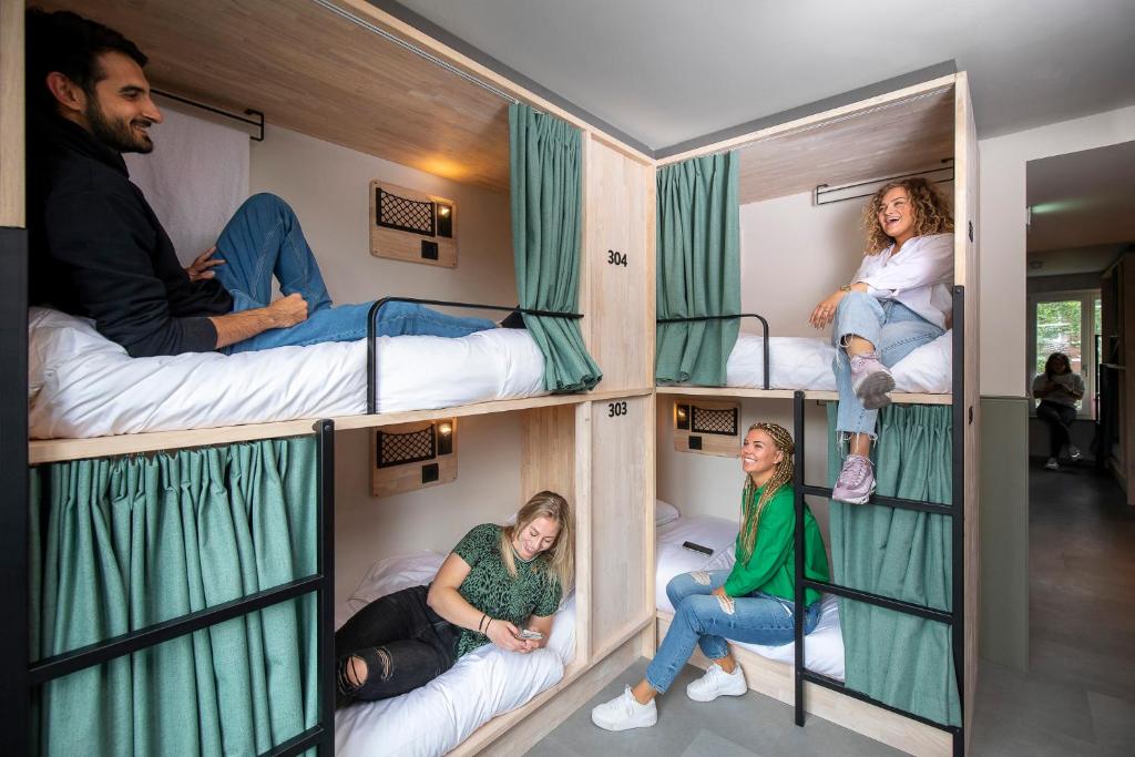 a group of people sitting in bunk beds in a room at The Bee Hostel in Amsterdam