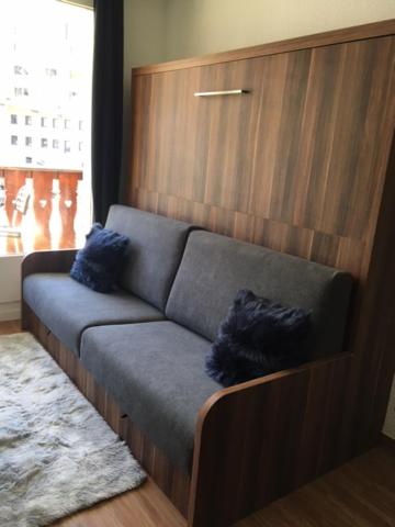 un sofá con dos almohadas azules en una habitación en studio cabine chalet club III entièrement rénové en Tignes