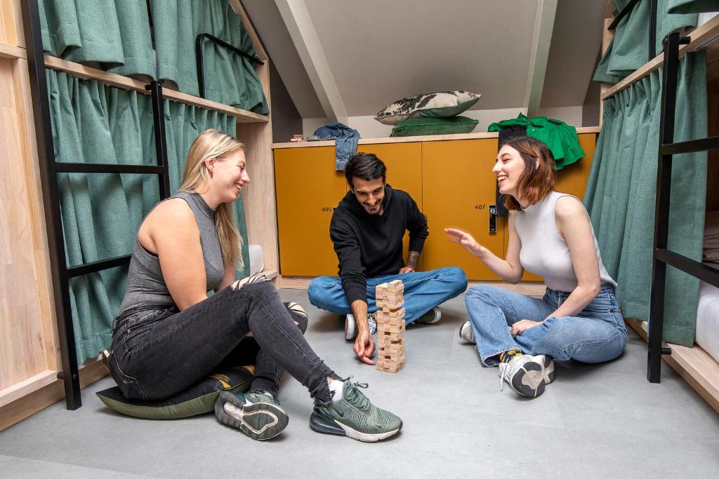 three people sitting on the floor in a room at The Bee Hostel in Amsterdam