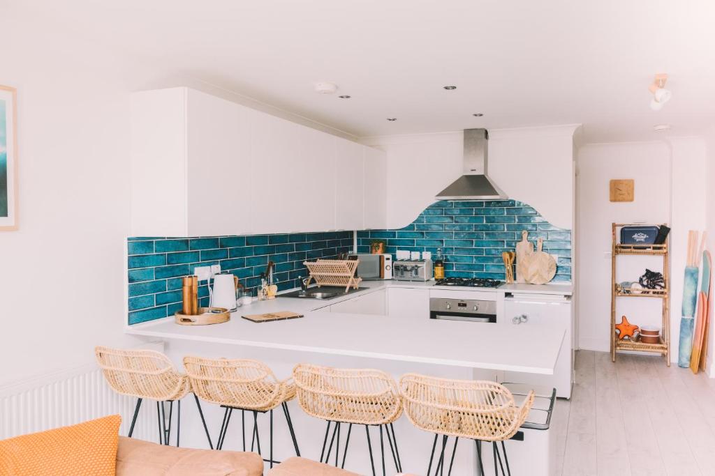 a kitchen with a white counter and some chairs at Pentire Point - Fully Equipped Eco Escape in Crantock