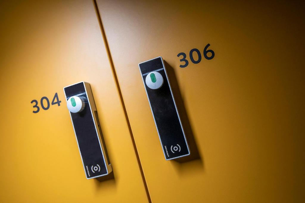 a pair of thermostats on a yellow wall with numbers at The Bee Hostel in Amsterdam