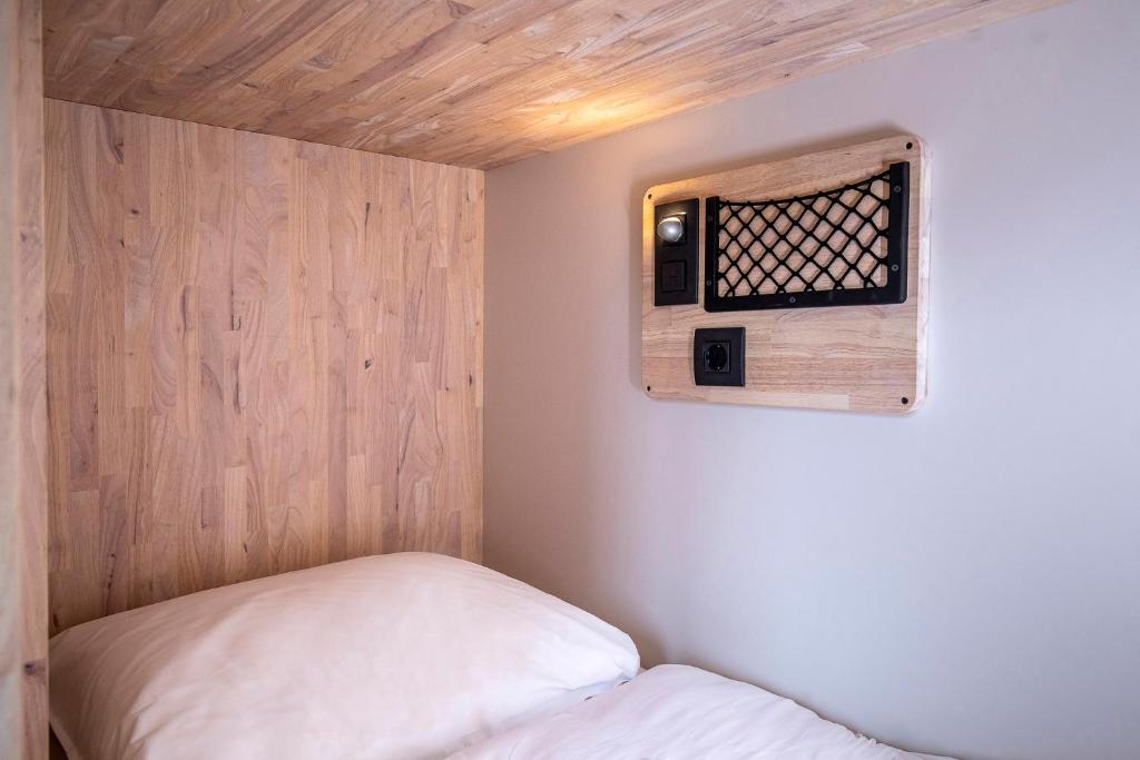 a small room with a bed and a wooden wall at The Bee Hostel in Amsterdam