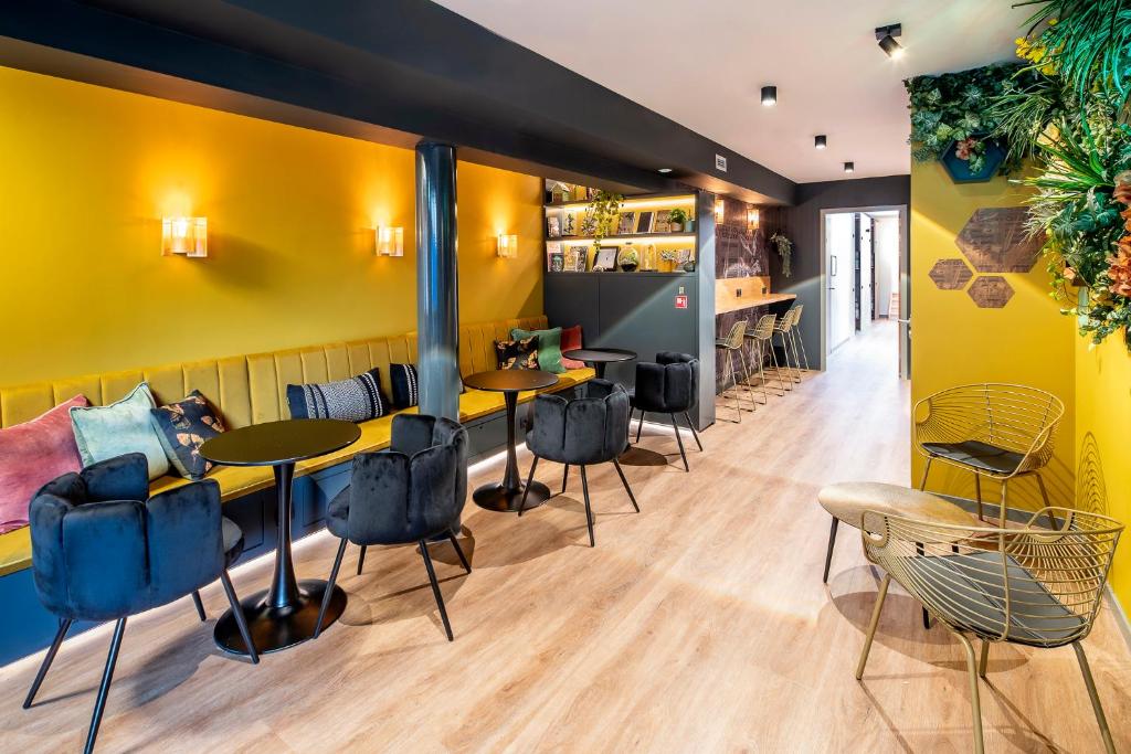 a restaurant with yellow walls and tables and chairs at The Bee Hostel in Amsterdam