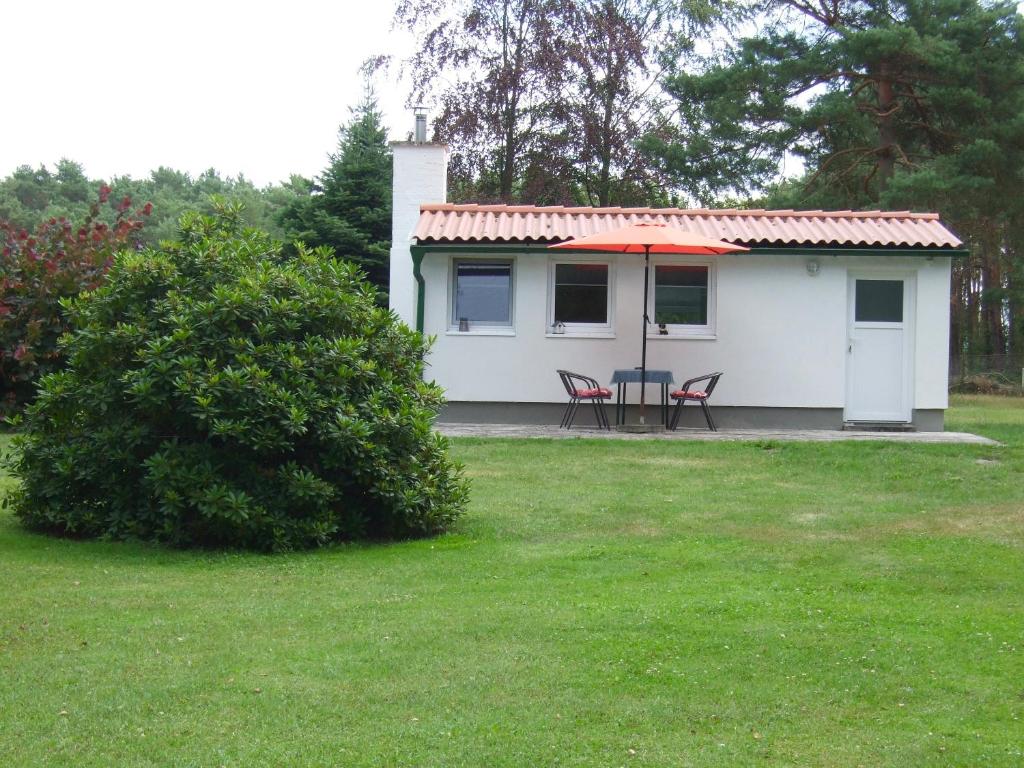 a small white house with a table and chairs in a yard at Ferienwohnung am See in Wochowsee