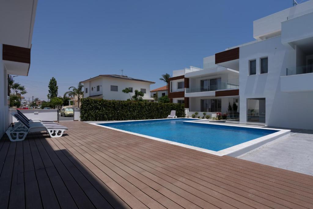 a swimming pool on a wooden deck next to a building at Lemon Tree 1-BR Apt in Livadia in Larnaka