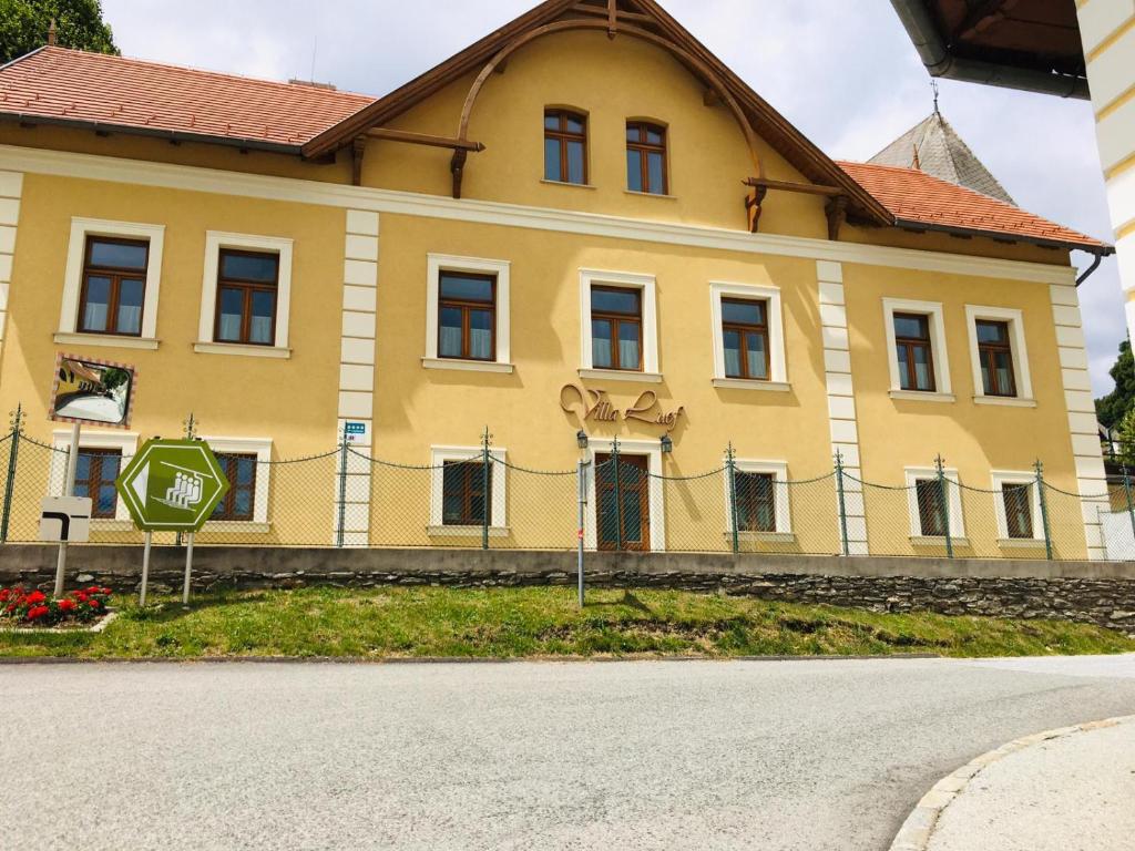 une maison jaune avec un panneau d'arrêt devant elle dans l'établissement Villa Luef, à Mönichkirchen