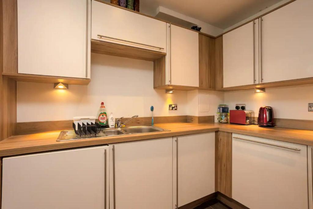 eine Küche mit weißen Schränken und einem Waschbecken in der Unterkunft Comfy 2 Bedroom Apartment near Edinburgh City Centre in Edinburgh