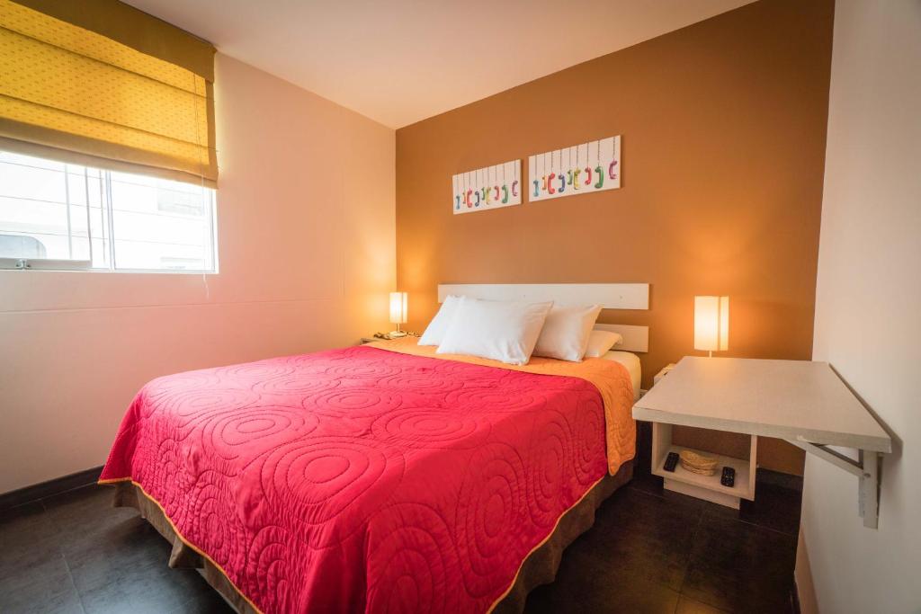 ein kleines Schlafzimmer mit einem roten Bett und einem Tisch in der Unterkunft B&B Wasi Airport Lima in Lima
