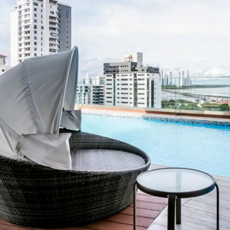 a chair and a table next to a swimming pool at Espectacular Apartamento con Piscina en Panamá in Panama City