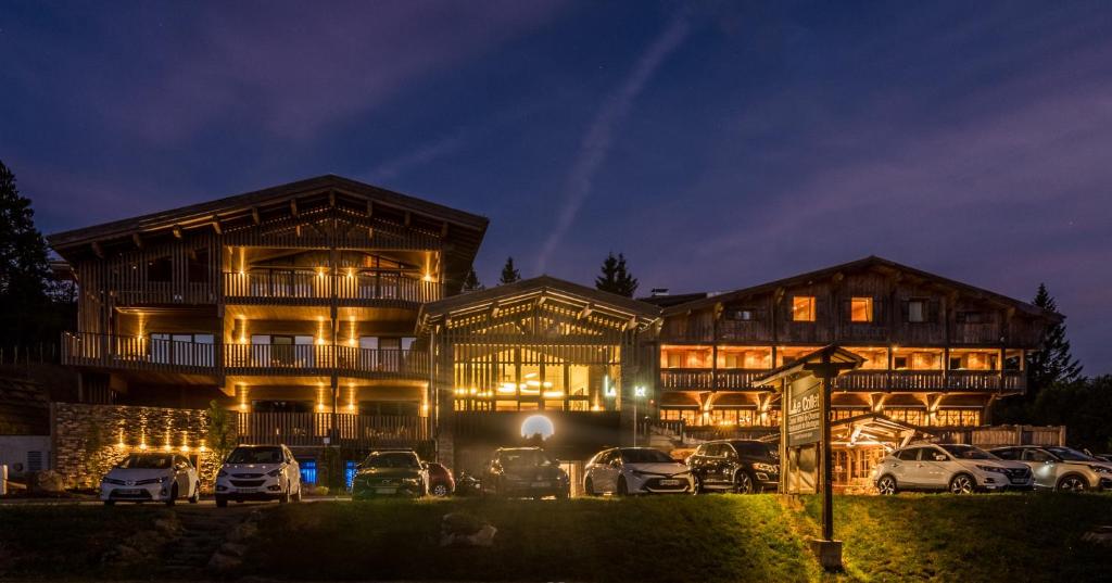 een gebouw waar 's nachts auto's voor geparkeerd staan bij Chalet Hotel Le Collet in Xonrupt-Longemer