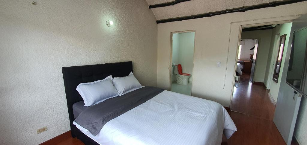 1 dormitorio con 1 cama con sábanas y almohadas blancas en Portal Norte 170 ACOGEDORAS HABITACIONES CON TODOS LOS SERVICIOS, en Bogotá