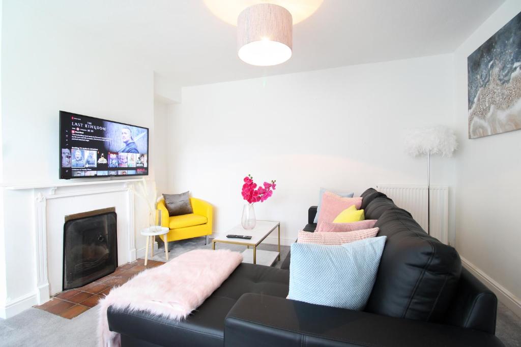 a living room with a black leather couch and a fireplace at Virexxa Aylesbury Centre - Deluxe Suite - 3Bed House with Free Parking in Aylesbury