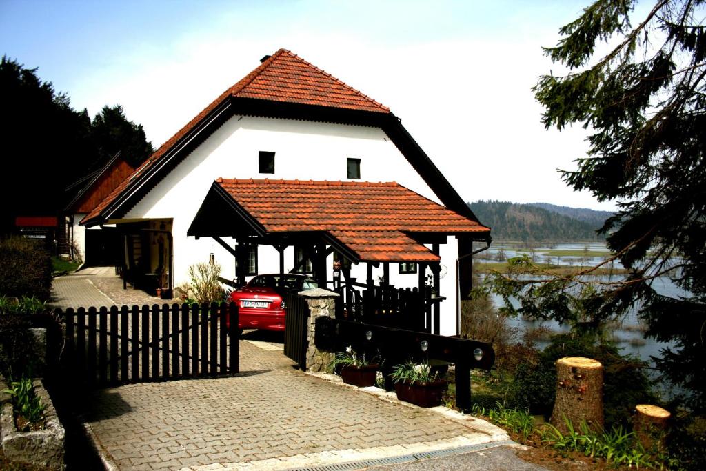 a white house with a red roof and a fence at Apartment Šefic in Planina