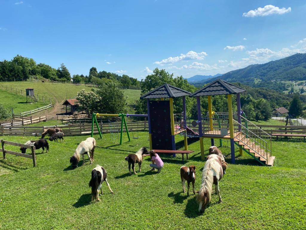 un grupo de cabras pastando en un campo con parque infantil en Apartments Laura FARM STAY en Podčetrtek