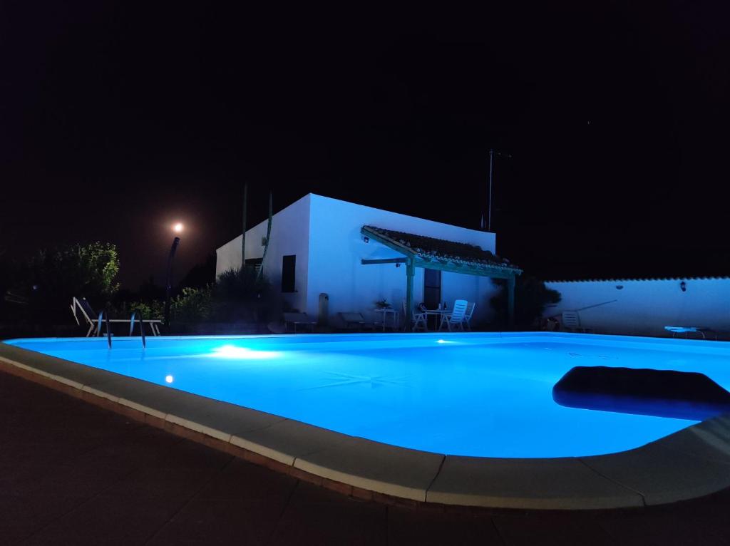 een groot zwembad dat 's nachts verlicht wordt bij il Cigno Reale-Green-Rooms Leasing Touristic Ragusa in Chiaramonte Gulfi