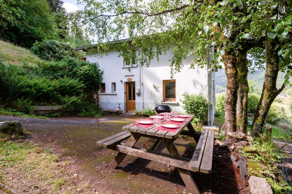 a picnic table in front of a white house at La Vallée de Ventron in Ventron