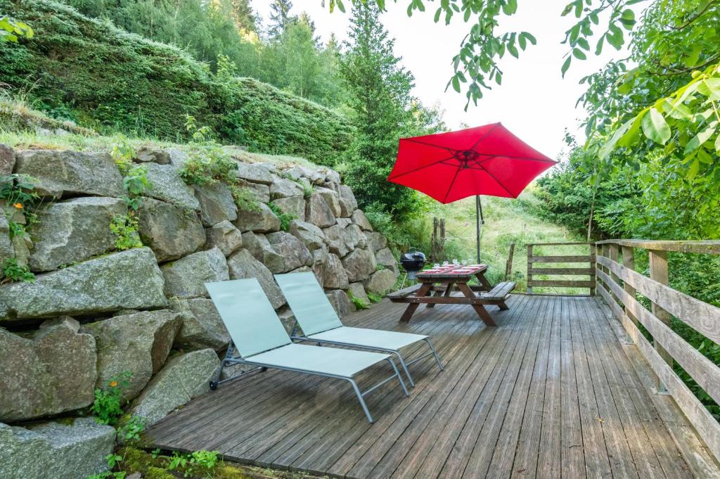 une terrasse en bois avec une table et un parasol rouge dans l'établissement Les Pistes de Ventron, à Ventron