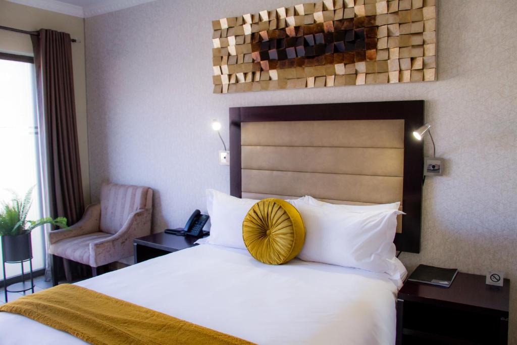 a hotel room with a bed with a yellow pillow on it at Q's Boutique Stay in Standerton