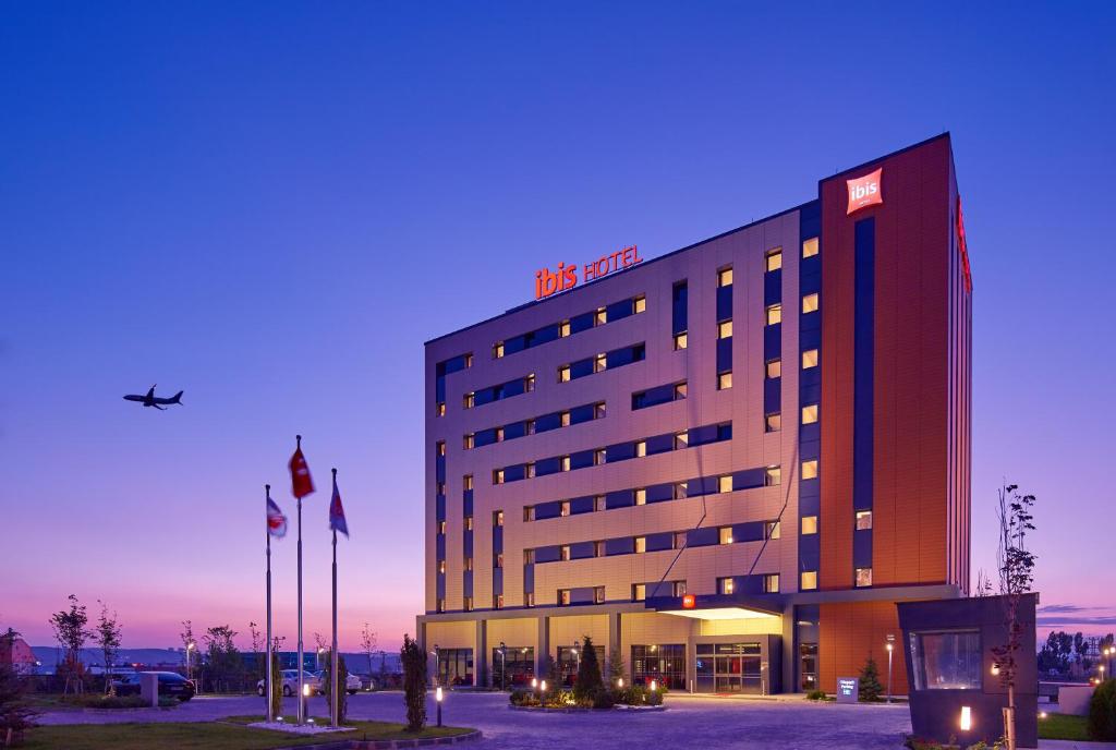 a hotel building with a plane flying in the sky at ibis Ankara Airport Hotel in Ankara