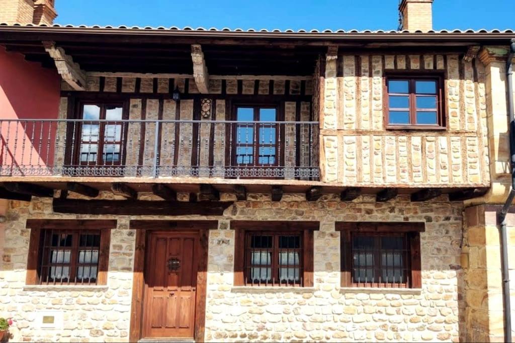 Casa antigua con balcón y puerta de madera. en El Limonero, en Arenas de Iguña