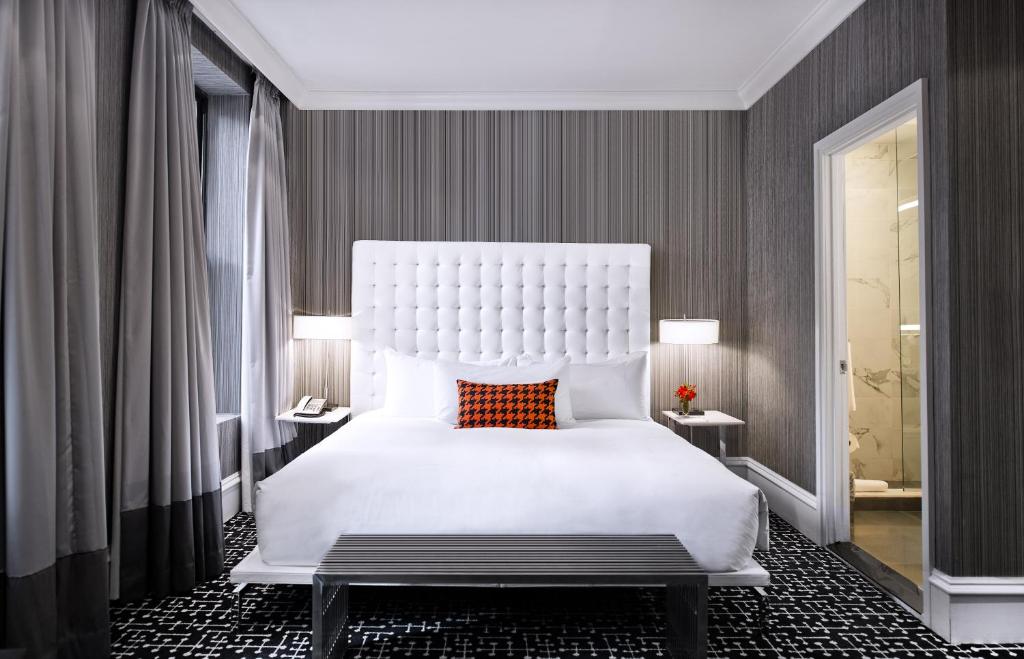 فندق مودرن في نيويورك: غرفة نوم بسرير ابيض كبير ومخدة حمراء