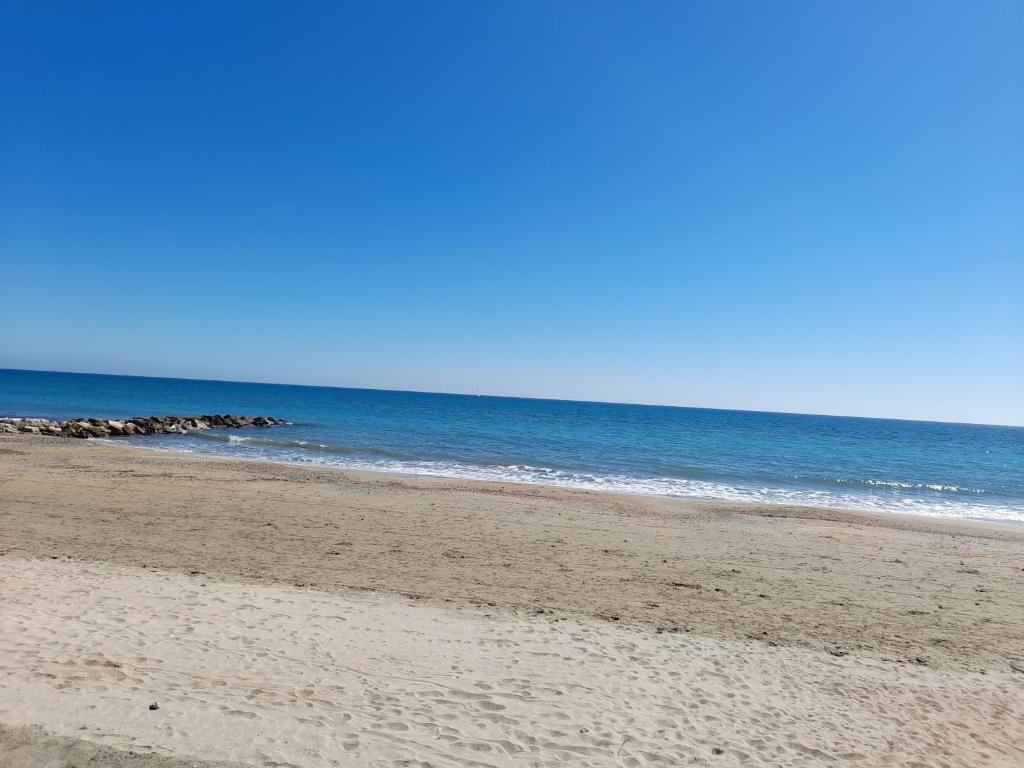 una spiaggia sabbiosa con l'oceano sullo sfondo di JOLI T2 RDC, BORD DE MER , PISCINE , Aresquiers FRONTIGNAN PLAGE 34 a Frontignan