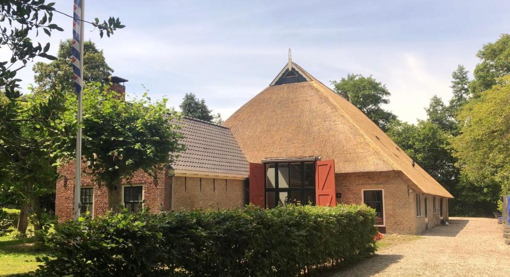 een oud bakstenen gebouw met een driehoekig dak bij Landgoed Olterterp Lodges, kies een comfortabel huisje of appartement op de allermooiste locatie in Olterterp