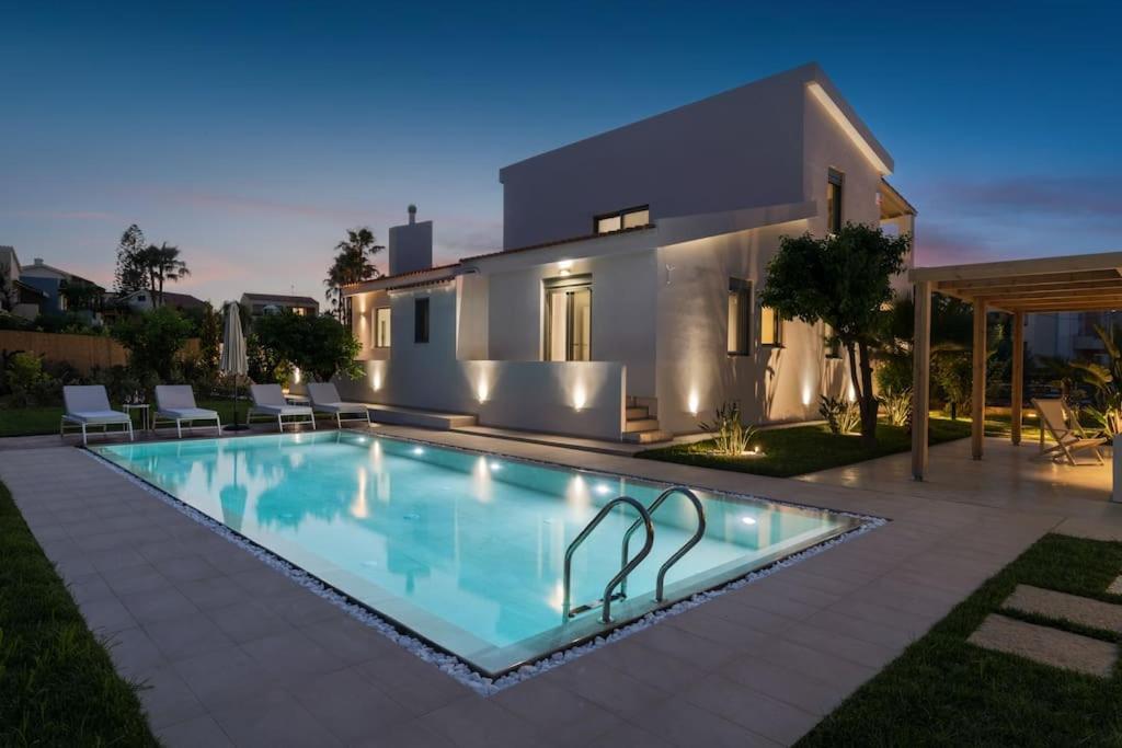 a villa with a swimming pool in front of a house at Villa Elora Platanias in Plataniás