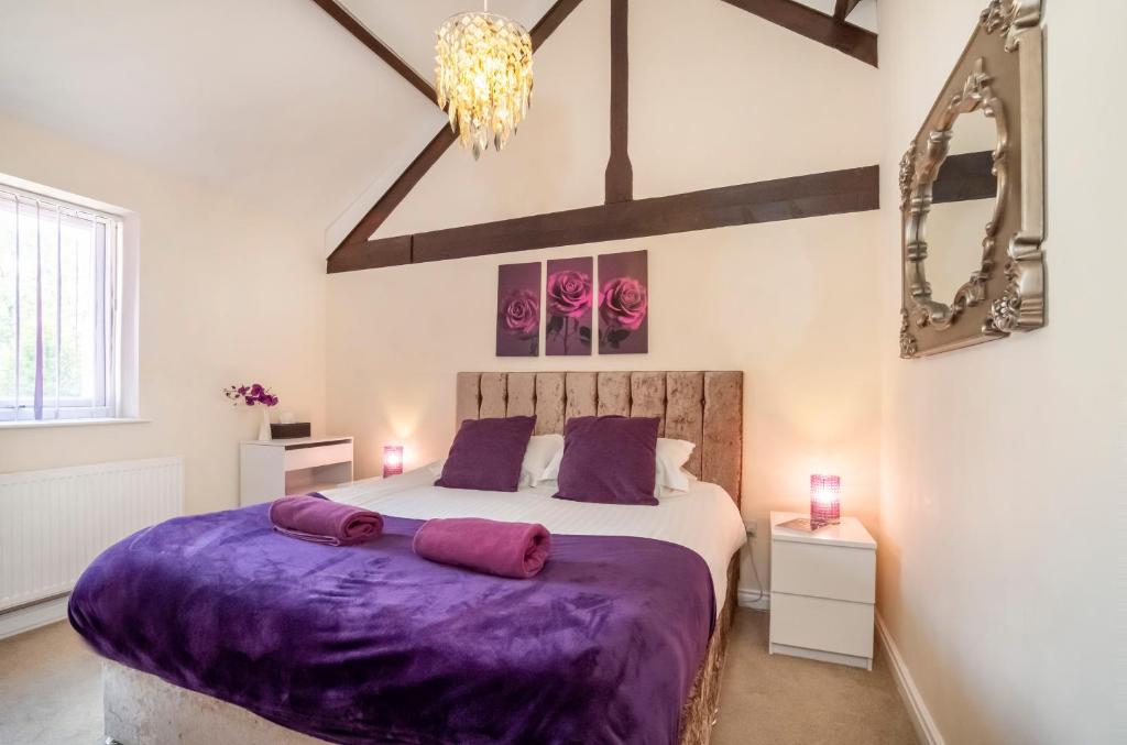 a bedroom with a large bed with purple sheets at 1 Ascot Mews - City of York Holiday Home in York