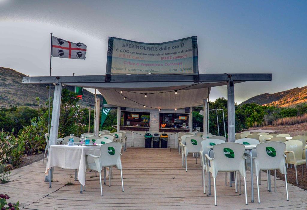 a restaurant with white tables and chairs and a sign at Hotel L'Oleandro in Villasimius