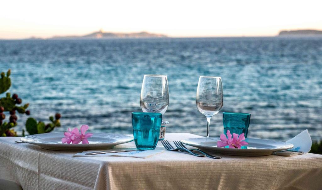 a table with two plates and glasses on the water at Hotel L'Oleandro in Villasimius