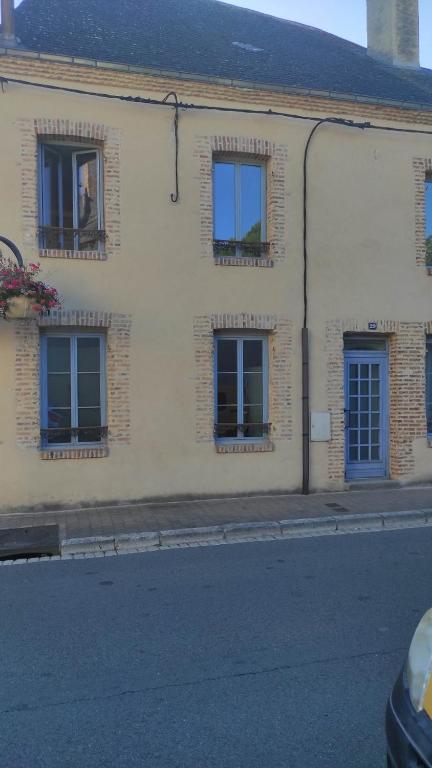 een wit gebouw met blauwe ramen op een straat bij AUBIGNY SUR NERE in Aubigny-sur-Nère