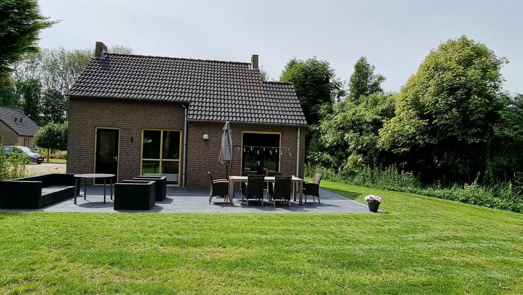 a house with a patio with tables and chairs at Recreatiewoning Maas en Waal 72 in Ewijk