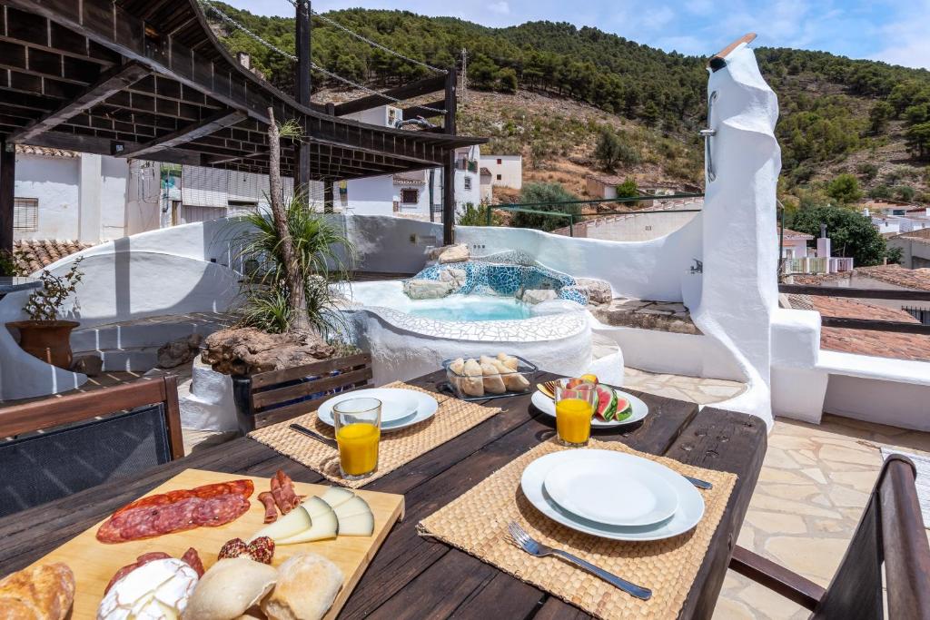 a table with food and drinks on a patio with a pool at Town house with roof terrace and plunge pool in Alcaucín
