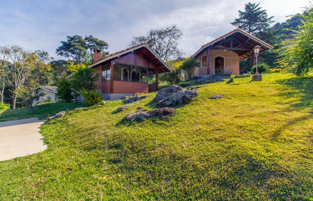 uma casa numa colina relvada com uma casa em Chales Estrada de Chão em Monte Verde